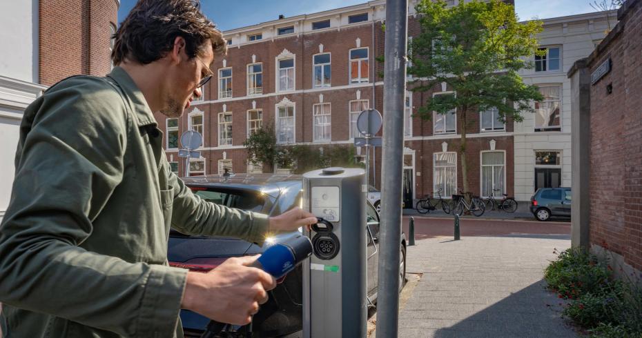 Man laadt elektrische auto in de straat bij publieke laadpaal Velian