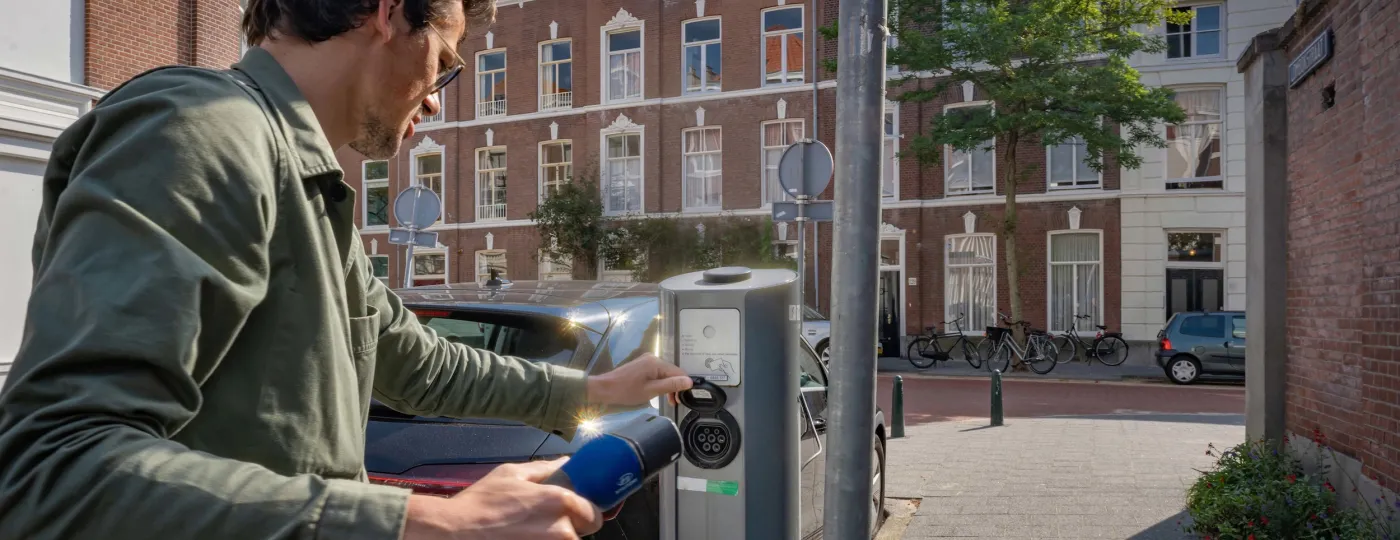 Man laadt elektrische auto in de straat bij publieke laadpaal Velian
